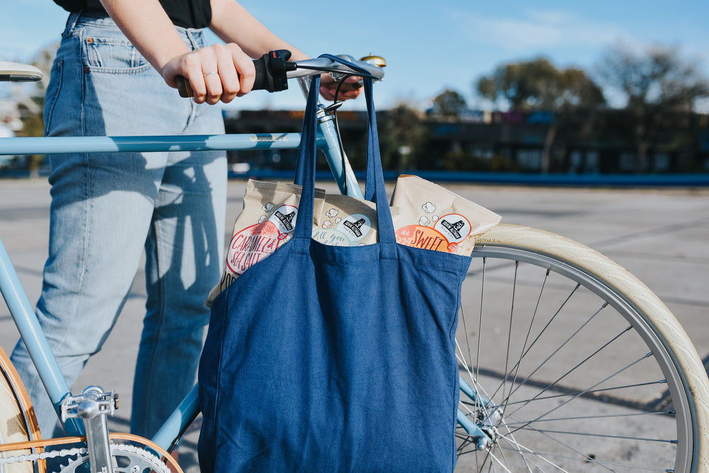 A person with a light blue bike carrying a dark blue bag full of popcorn.